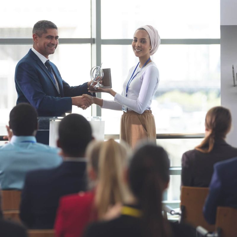 businesswoman-receiving-award-from-businessman-at-a-business-seminar-in-office-building-1.jpg